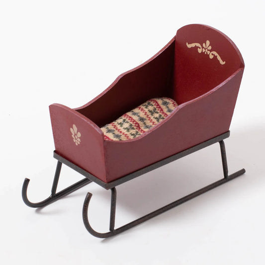a toy sleigh with a plaid blanket in it